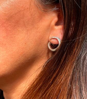 Modelo posando con elegantes pendientes de oro blanco con diamantes en forma ovalada que aportan brillo y sofisticación.