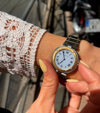 Modelo mostrando en la mano el icónico reloj Ronde con números romanos, elegantes agujas azules en forma de espada y distintivo cabujón de zafiro.