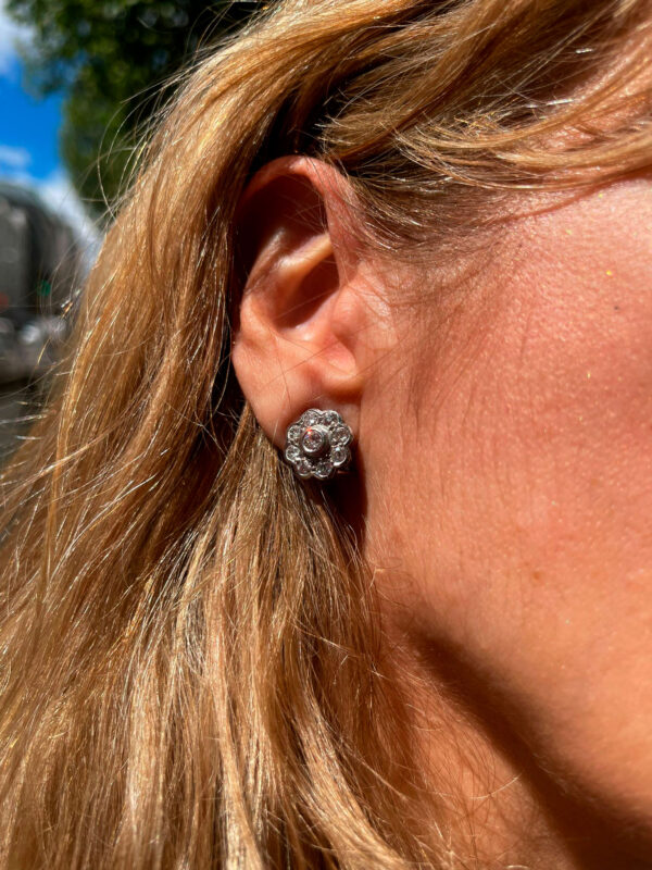 Modelo luciendo pendientes rosetón de oro y diamantes, una joya elegante que destaca por su brillo y diseño sofisticado.