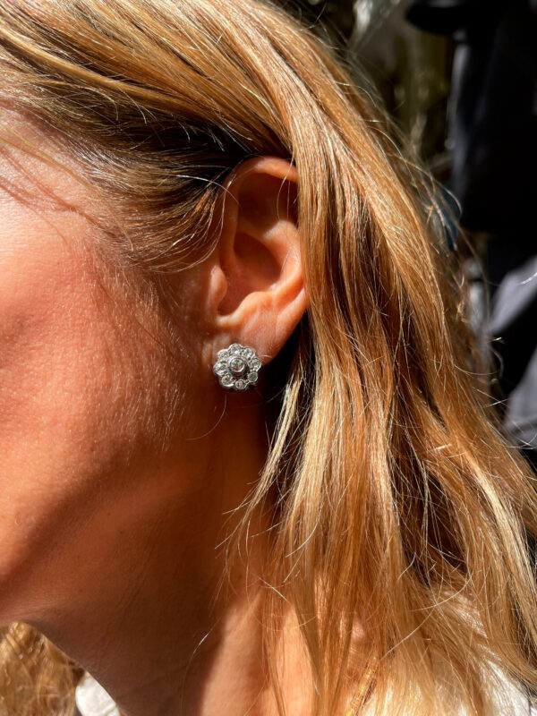 Modelo luciendo pendientes rosetón de oro y diamantes, una joya elegante que destaca por su brillo y diseño sofisticado.
