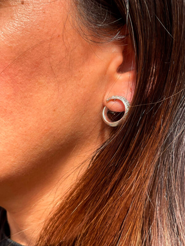 Modelo posando con elegantes pendientes de oro blanco con diamantes en forma ovalada que aportan brillo y sofisticación.