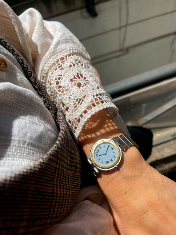 Primer plano de la mano de un modelo luciendo el sofisticado reloj Ronde con esfera de números romanos, agujas azules y exclusivo cabujón de zafiro.
