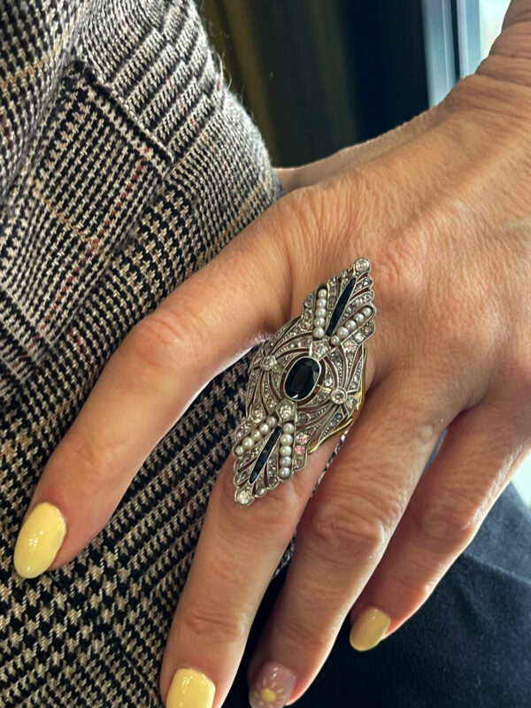 Sofisticada sortija de oro blanco adornada con un zafiro central y detalles de perlas que aportan un estilo elegante y exclusivo.