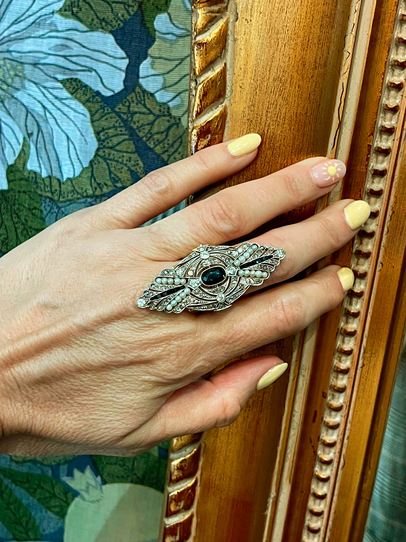 Sofisticada sortija de oro blanco adornada con un zafiro central y detalles de perlas que aportan un estilo elegante y exclusivo.
